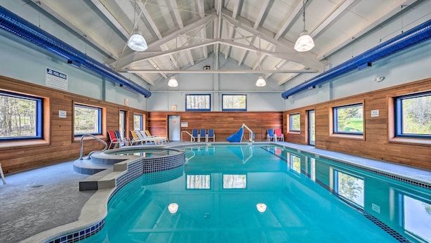An indoor swimming pool with clear blue water, wooden walls, and large windows. - Timber Creek Townhome w/ 2 Decks & Mtn Views! (West Dover)