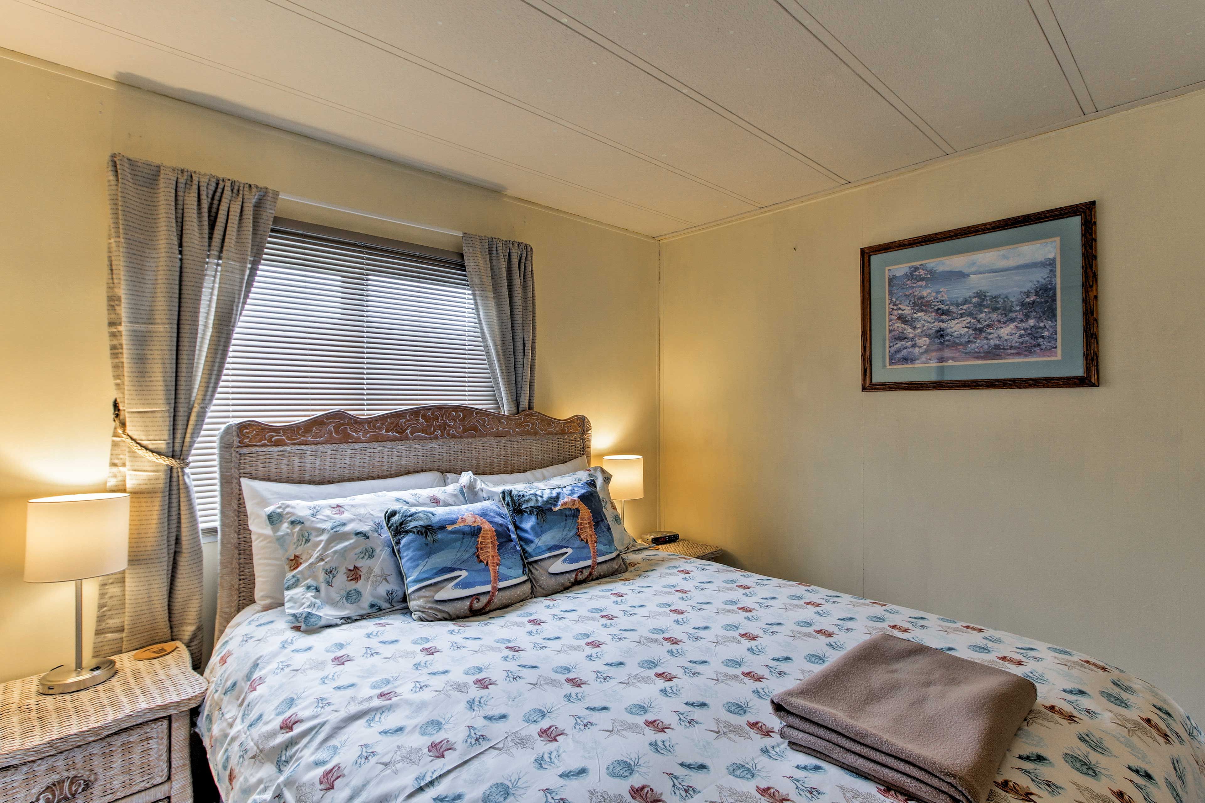 A neatly made bed with patterned bedding, a bedside lamp, and a framed picture on the wall.