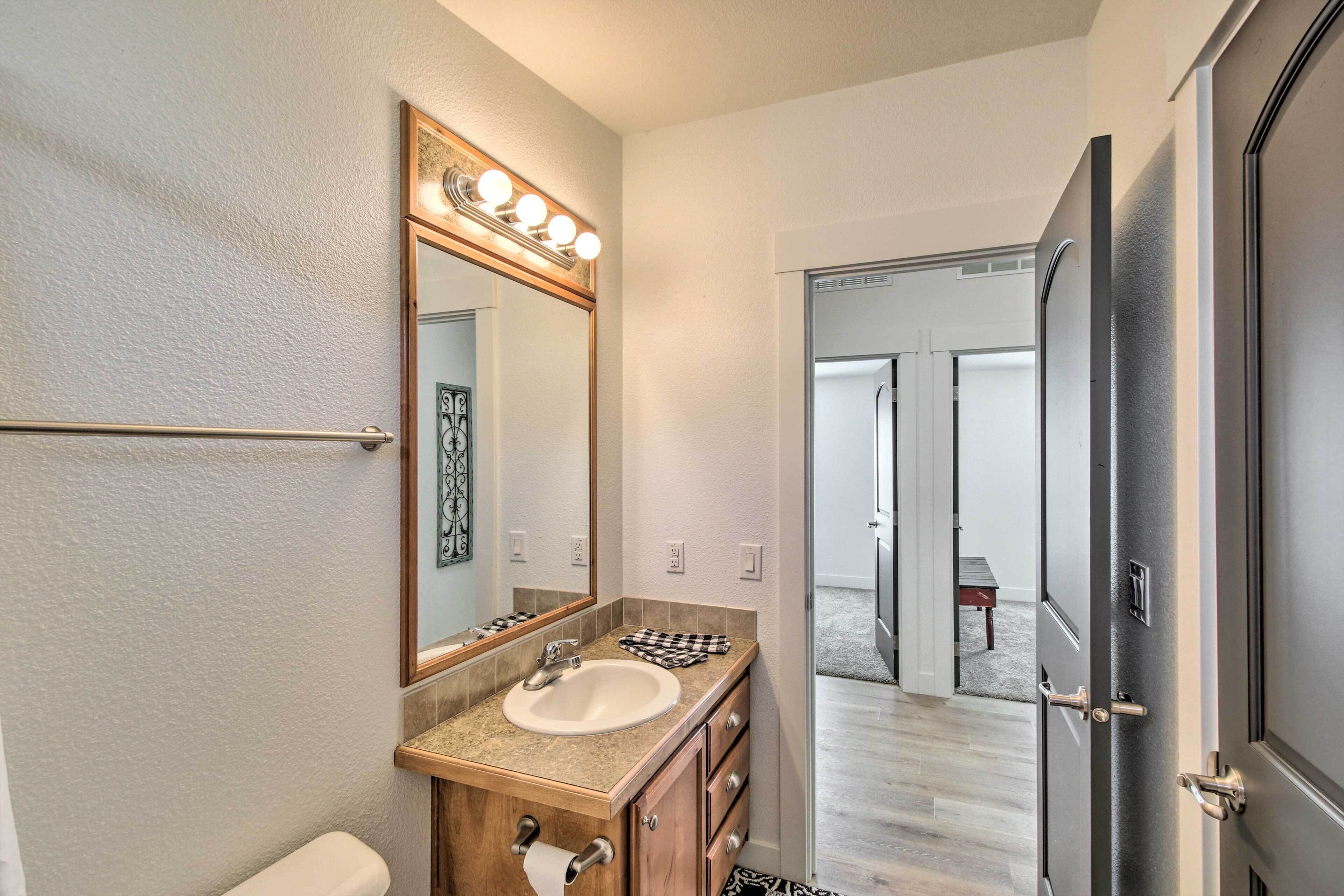 Un baño con tocador, lavabo, espejo y barra para toallas.
