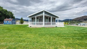 A single-story house with a porch, surrounded by a well-maintained lawn, under a cloudy sky. - Tranquil Indigo Getaway < 3 Mi to Hot Pools! (Lava Hot Springs)