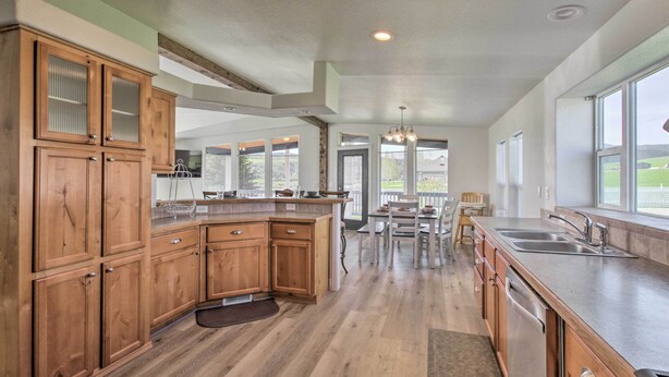 A spacious kitchen with wooden cabinets, a large island, and a view to the outdoors. - Tranquil Indigo Getaway < 3 Mi to Hot Pools! (Lava Hot Springs)