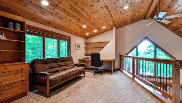 A cozy room with a wooden ceiling, a sofa, a desk, and a view of the outdoors. - Waterfront Highland Lake Home w/ Deck + Dock (Highland Lakes)