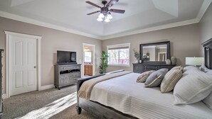 A bedroom with a bed, a ceiling fan, a dresser, a television, and a window. - Spacious Idaho Home: Ski, Hike, & Fish! (Rexburg)