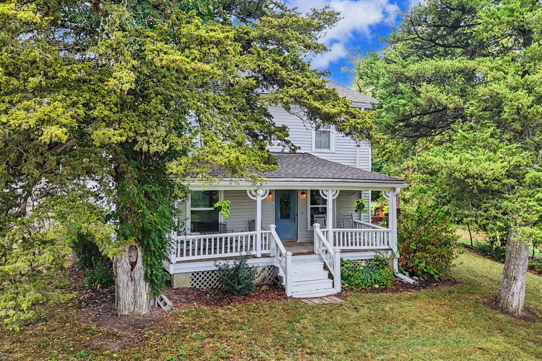 A two-story house with a front porch, a covered entryway, and a small front yard.