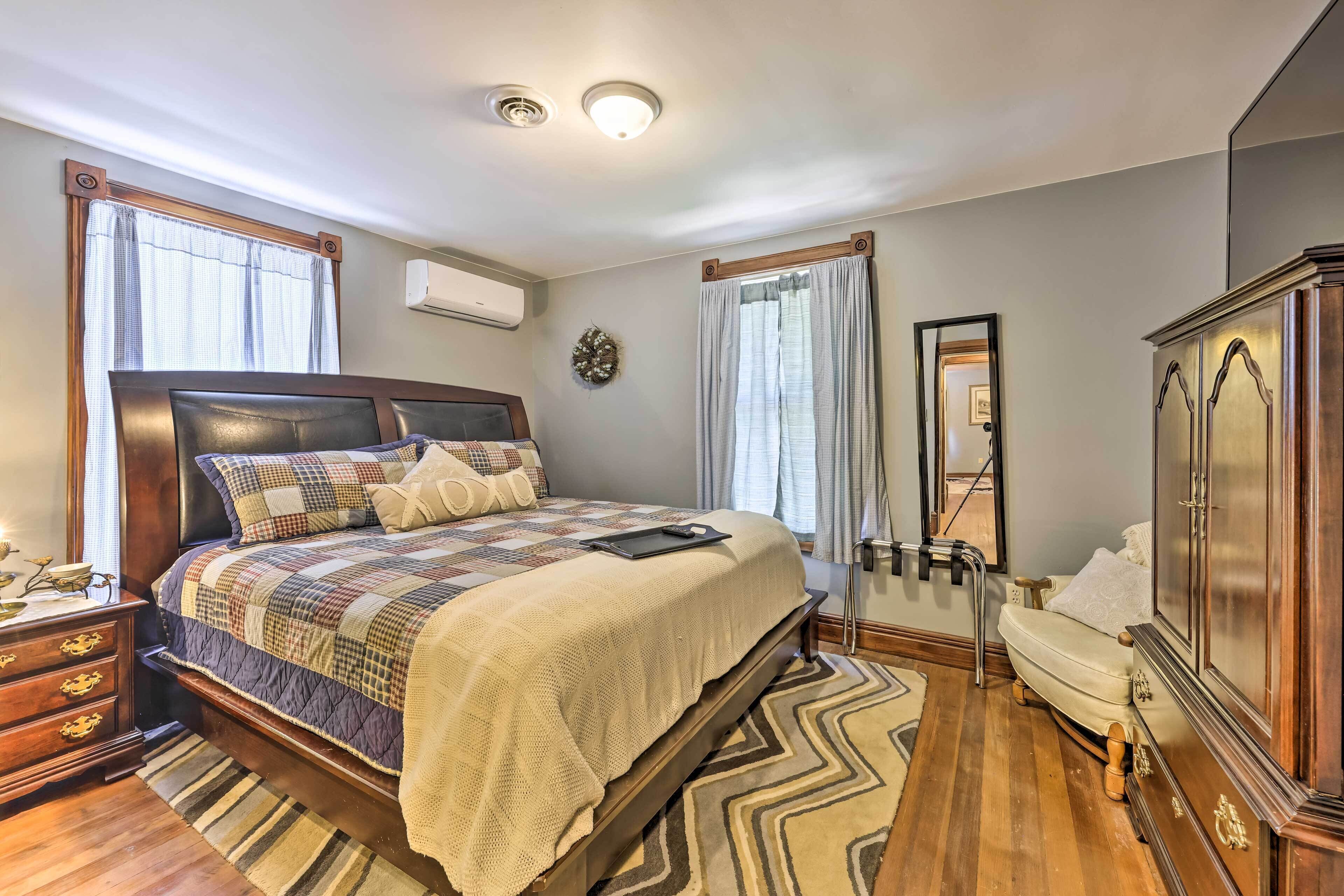 A bedroom with a large bed, a dresser, a vanity, and a mirror.