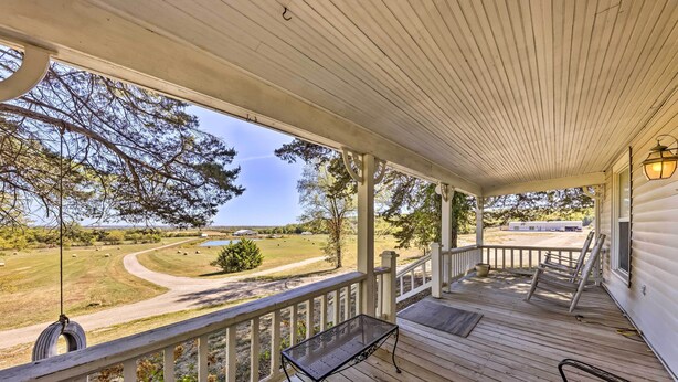 A covered porch with a view of a grassy area and trees. - The Farmhouse at Deer Ridge Estate (Tonganoxie)
