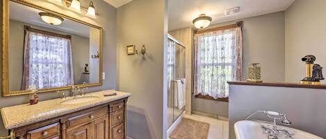 A bathroom with a wooden vanity, a large mirror, a bathtub, and a shower area.