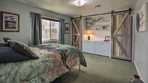 A bedroom with a bed, a dresser, a lamp, and a barn-style door. - Walkable Ten Sleep House w/ Patio & Sunroom! (Ten Sleep)