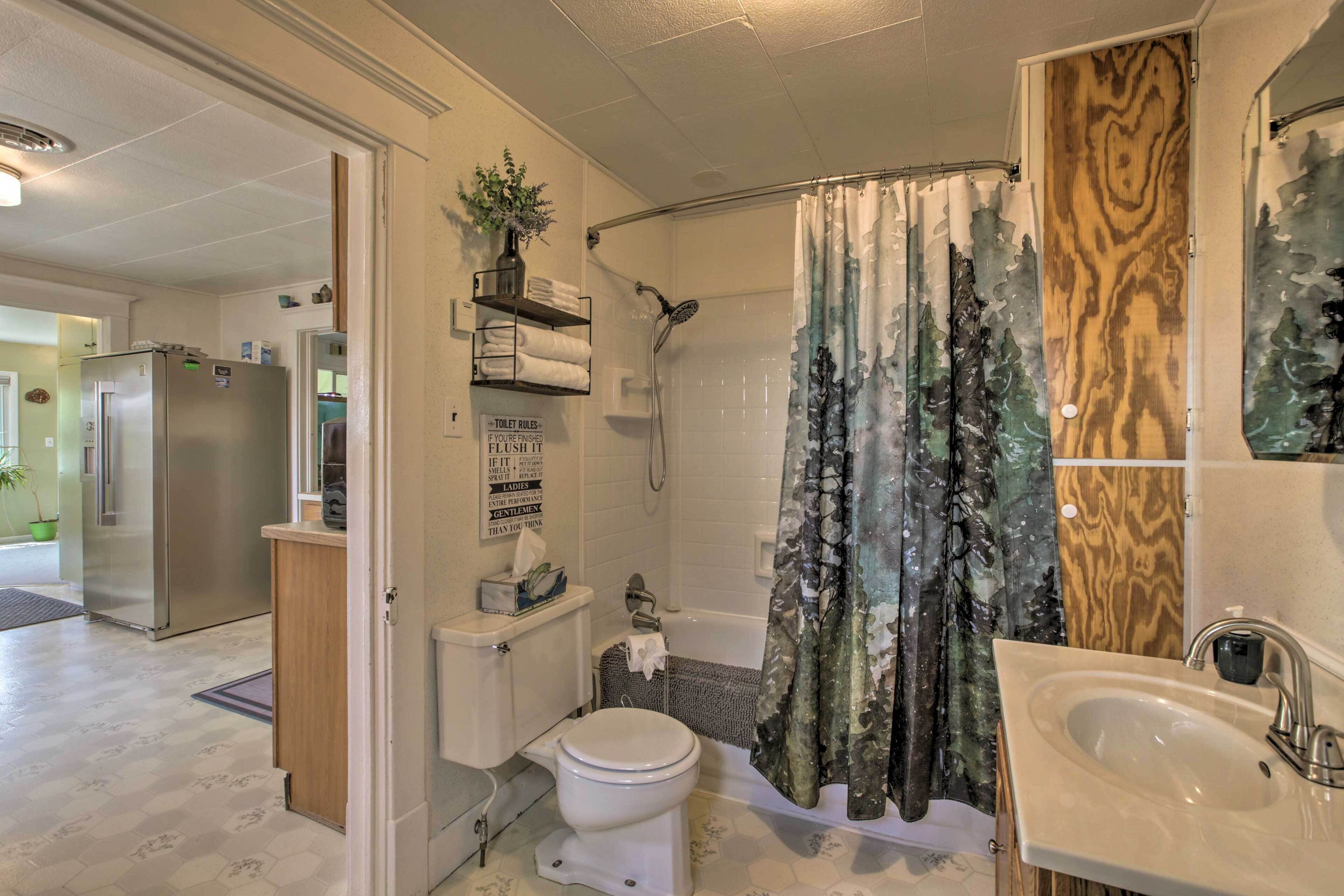 A bathroom with a shower, toilet, sink, and a wooden cabinet.
