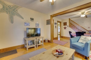A living room with a television, a blue sofa, a wooden coffee table, and a staircase leading to another level.