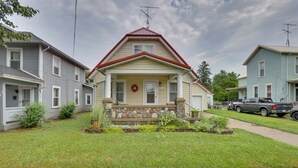 A two-story residential building with a red roof, stone foundation, and a front porch with a wreath. - Charming Urbana Home Near Downtown! (Urbana)