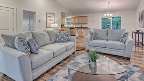 A modern living room with two grey sofas, a glass coffee table, and a kitchen in the background. - Unique Blue Ridge Haven, 12 Mi to Asheville! (Leicester)