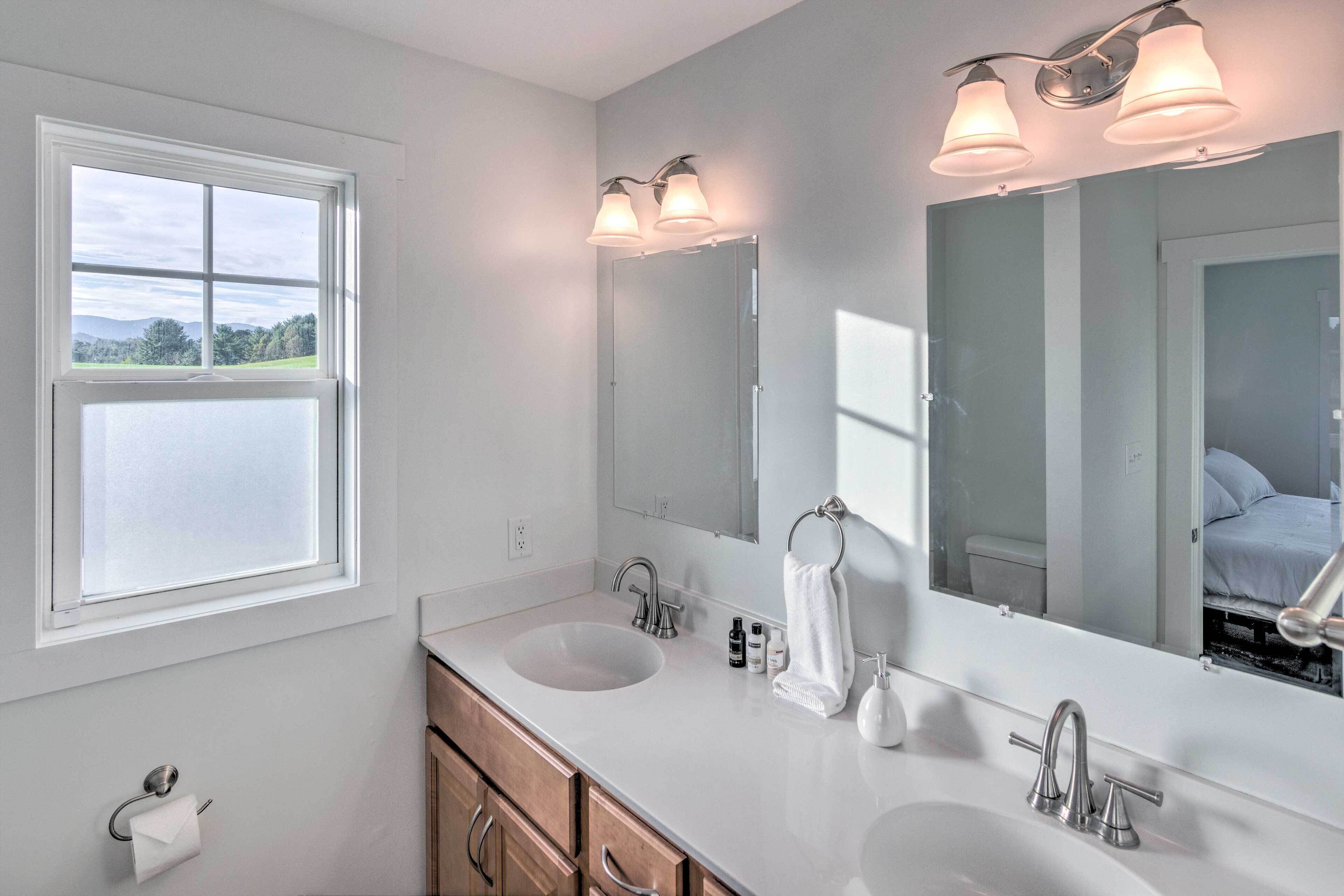 Une salle de bain avec deux lavabos, un grand miroir et une fenêtre donnant sur un lac.