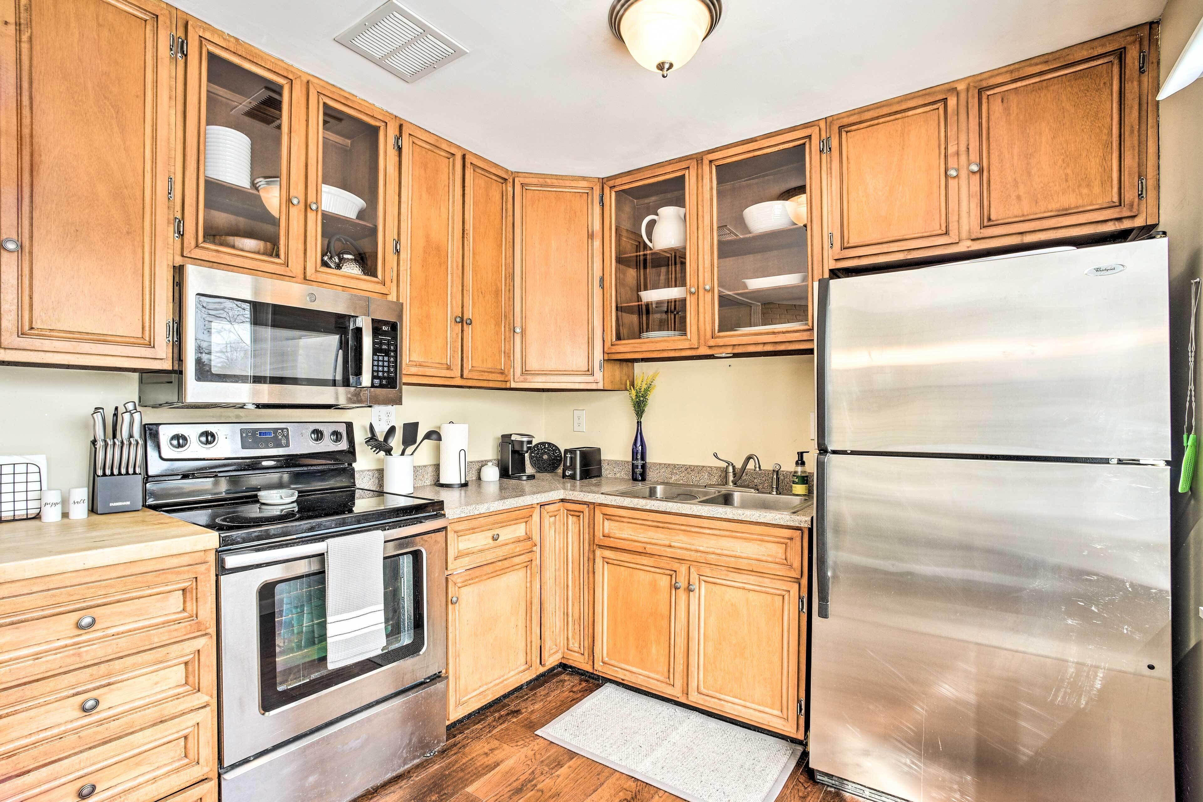 A kitchen with wooden cabinets, a stainless steel refrigerator, a microwave, and a stove.