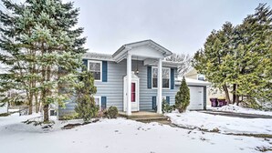 Une maison à deux étages avec un porche, un garage et de la neige au sol.