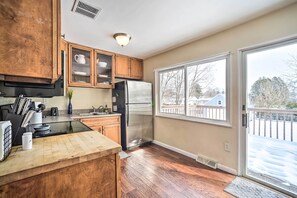 Eine Küche mit Holzausstattung, einem Edelstahlkühlschrank, einem großen Fenster und Blick auf eine verschneite Terrasse.