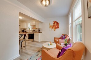 A modern living room with a sofa, coffee table, and a view of a kitchen and dining area. - 'the Blackberry Place' in Charlotte: Fire Pit (Charlotte)