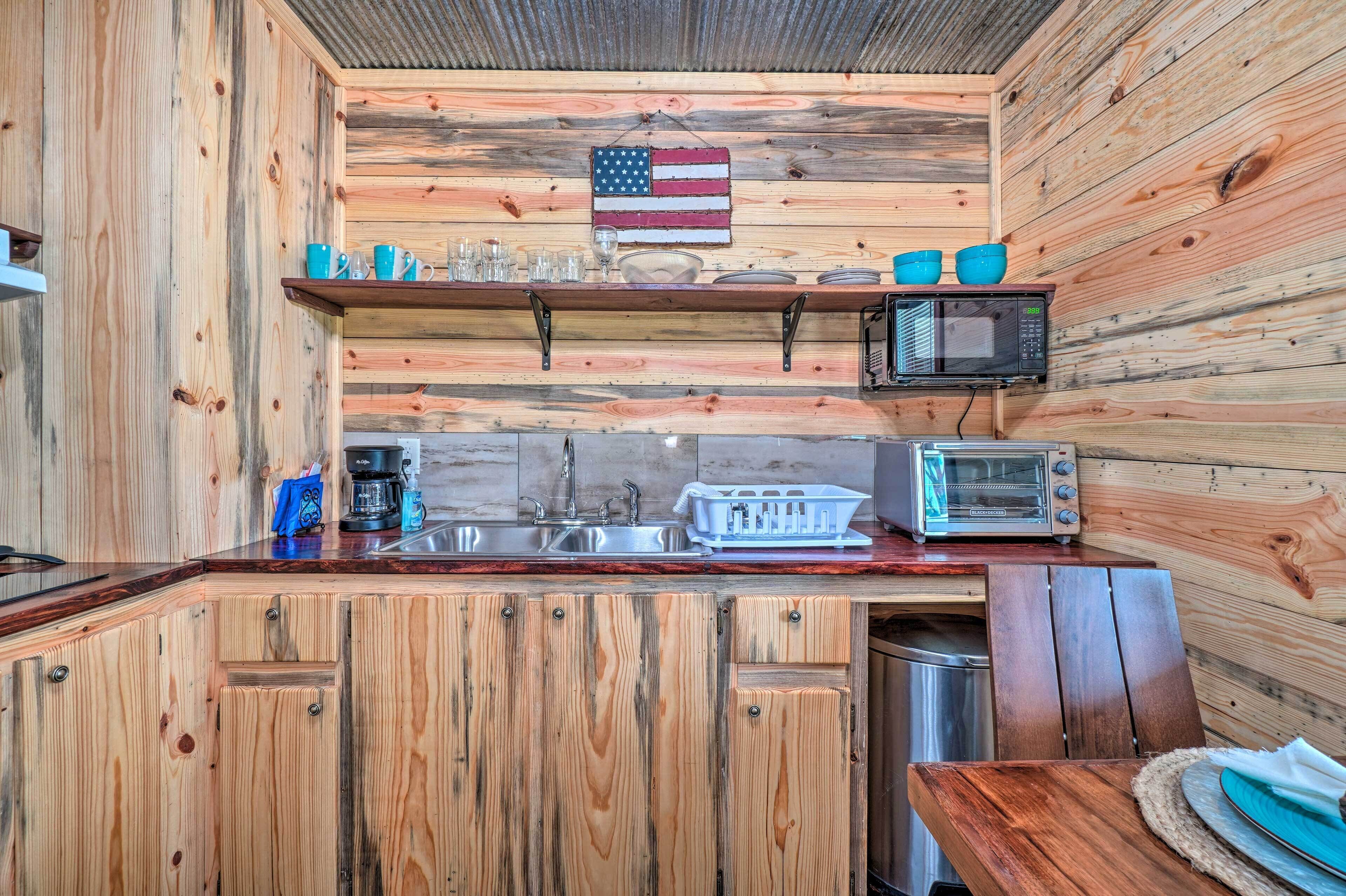 Una cocina rústica con paredes de madera, una encimera de madera, un fregadero, un microondas, un tostador y una bandera estadounidense colgada.