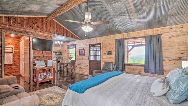 A wooden cabin interior with a bed, a desk, and a dining area.