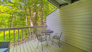 A covered outdoor area with a table and chairs, surrounded by a wooden deck and a railing. - Wintergreen Resort Studio w/ Deck & Ski-out Access (Nellysford)