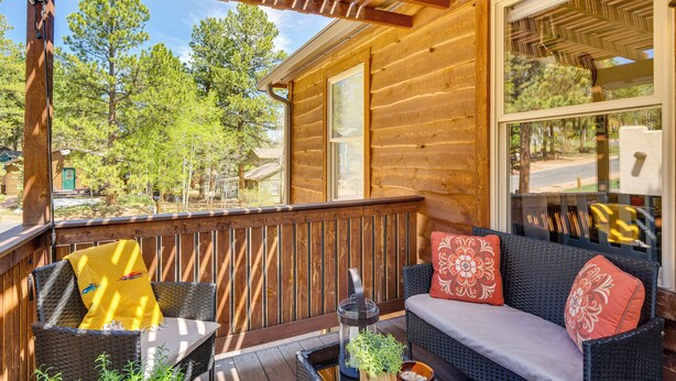 A wooden deck with wicker furniture and a glass door leading to a room. - Woodland Park Apartment: Forest Views + Deck! (Woodland Park)