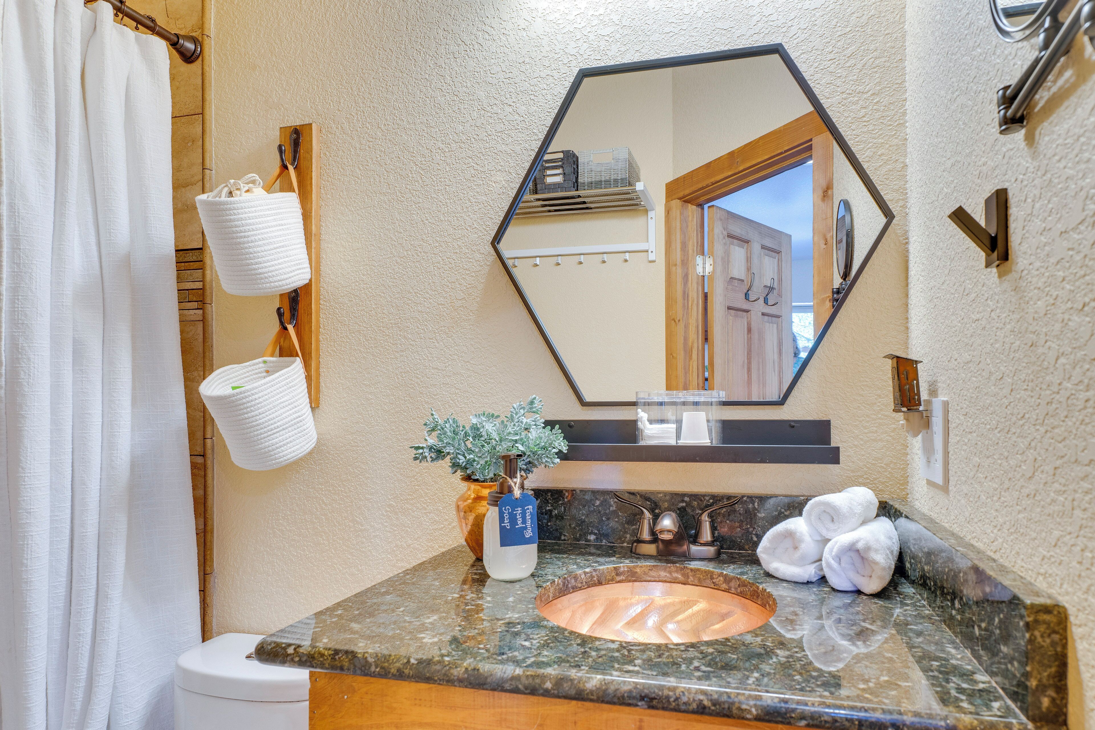 A bathroom with a marble sink, a mirror, a towel rack, and a potted plant.