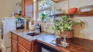 A kitchen with granite countertops, wooden cabinets, a built-in oven, and a window with a view of trees. - Woodland Park Apartment: Forest Views + Deck! (Woodland Park)