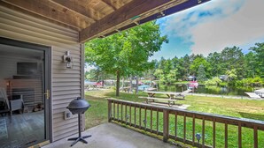 A covered porch with a grill, a view of a lake with boats, picnic tables, and a wooden deck railing. - Waterfront Crivitz Property w/ Lake Access! (Crivitz)