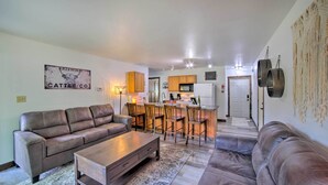 A living room with a brown leather sofa, a wooden coffee table, and a patterned rug. There is a kitchen area with wooden cabinets and a microwave. - Waterfront Crivitz Property w/ Lake Access! (Crivitz)