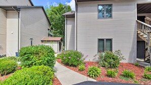 A two-story residential building with a covered outdoor area, a pathway, and various shrubs and flowers. - Waterfront Crivitz Property w/ Lake Access! (Crivitz)