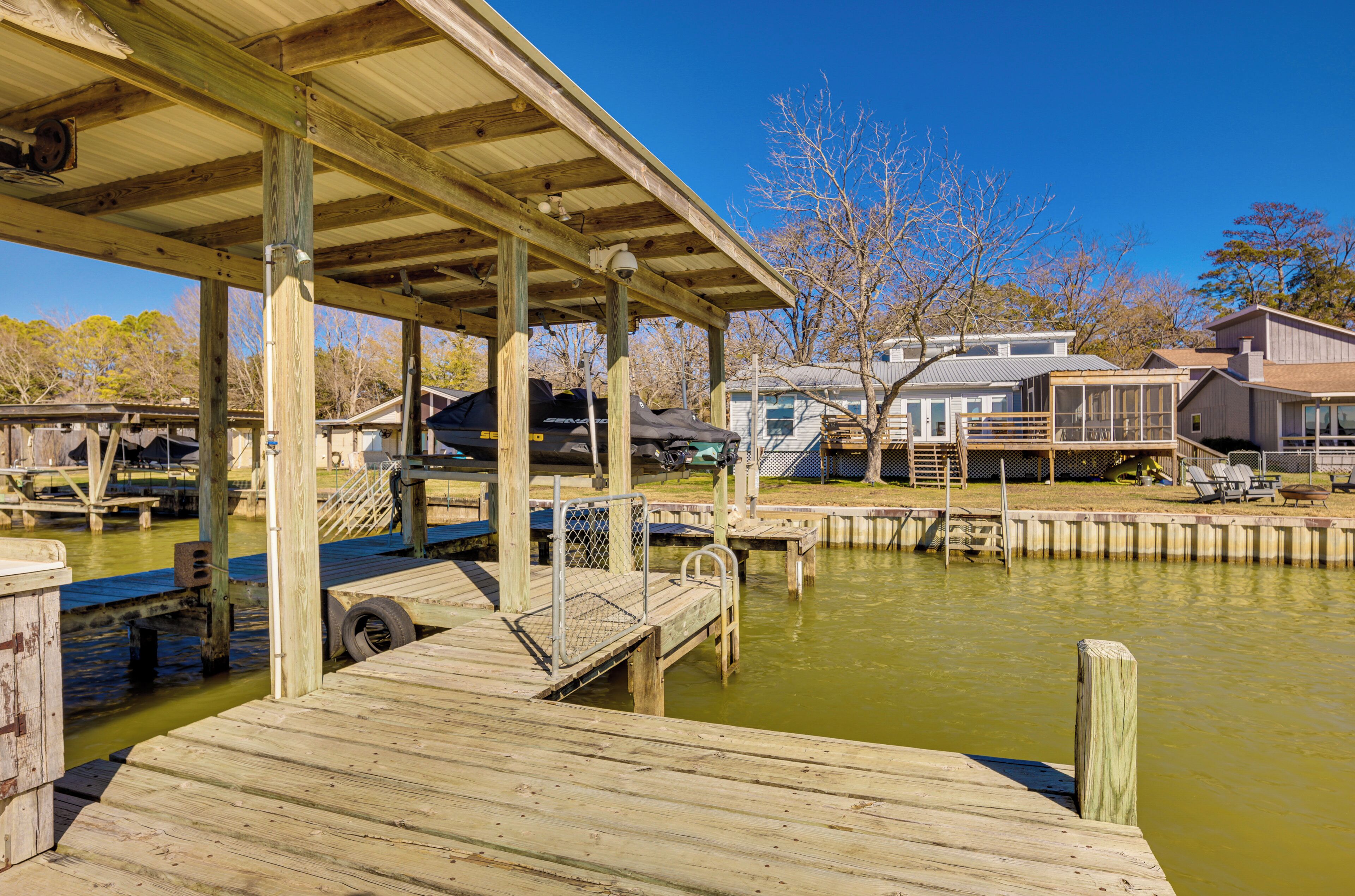 A wooden dock extending into a body of water with a covered area overhead.