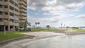 A beachfront hotel with a sandy beach, palm trees, and a view of the sea. - Waterfront Gulf Shores Condo w/ Patio, Pier & Pool (Gulf Shores)
