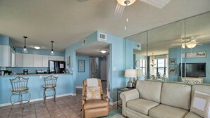 A spacious living area with a beige sofa, a recliner, and a bar area with stools. - Waterfront Gulf Shores Condo w/ Patio, Pier & Pool (Gulf Shores)
