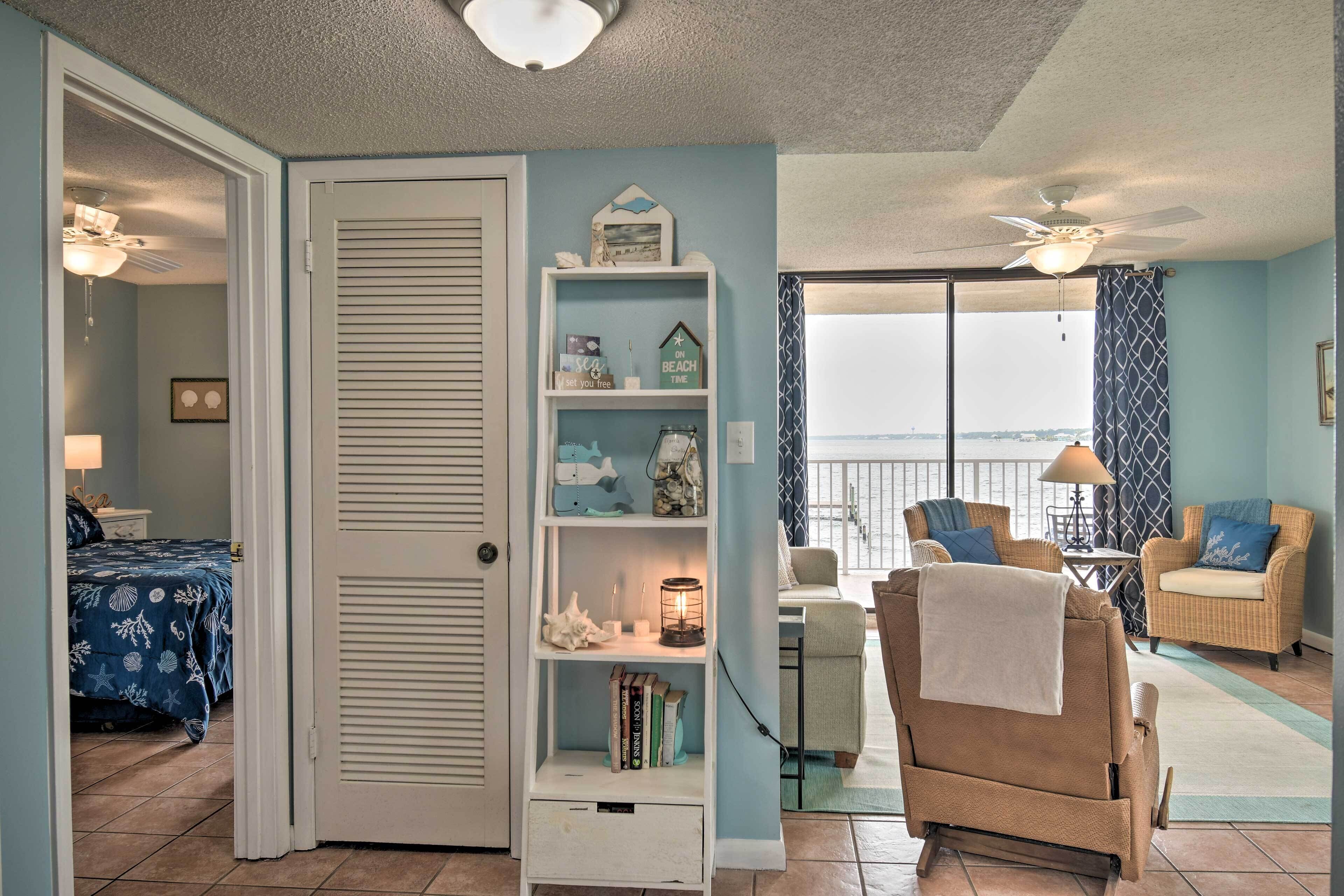 A room with a large sliding door, a bookshelf, a chair with a towel, and a view through a large window.