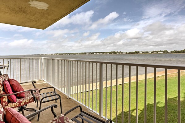A balcony with a view of a body of water, a railing, and a lawn.