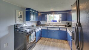 A kitchen with blue cabinets, a stainless steel refrigerator, and a wooden floor. - Albany Family Lake Getaway Near State Parks! (Albany)