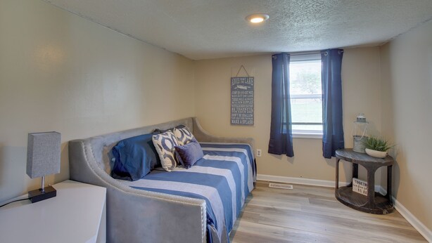 A bedroom with a bed, bedside table, lamp, and a window with curtains.
