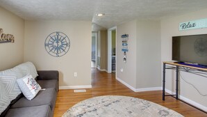 A living room with a gray sofa, a round rug, a wall clock, and a TV on a stand. - Albany Family Lake Getaway Near State Parks! (Albany)