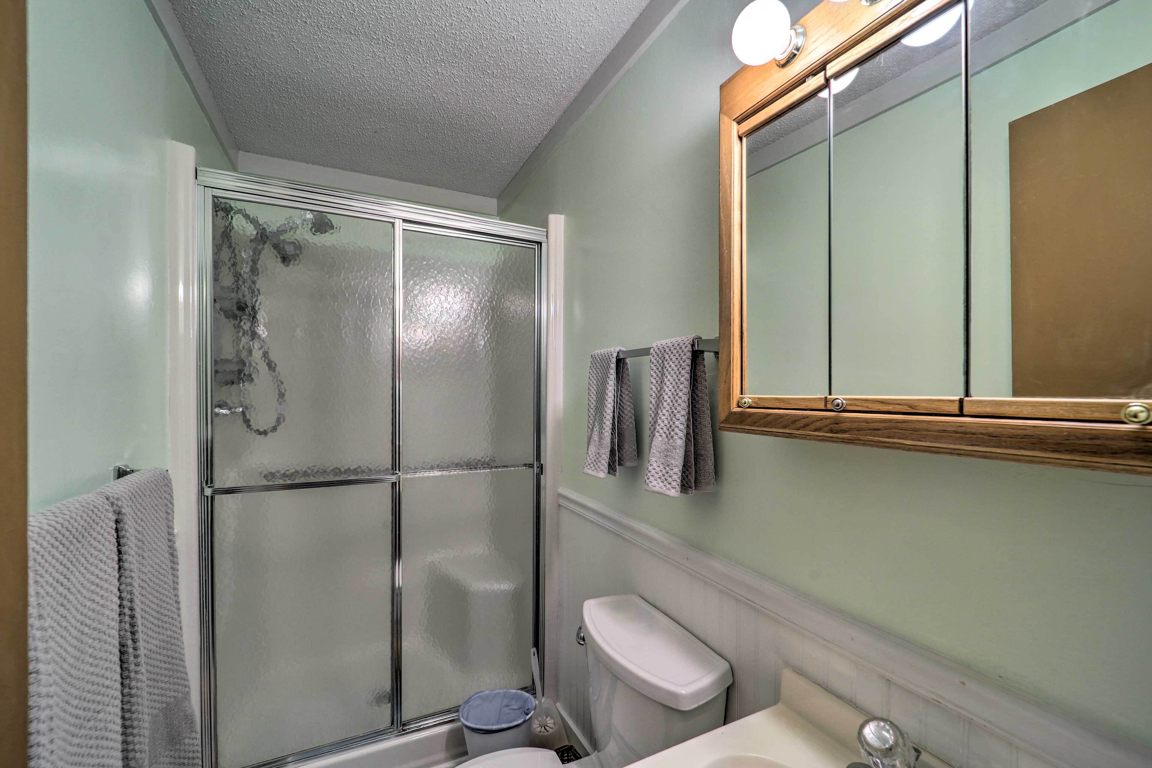 A bathroom with a glass shower enclosure, a toilet, and a sink.