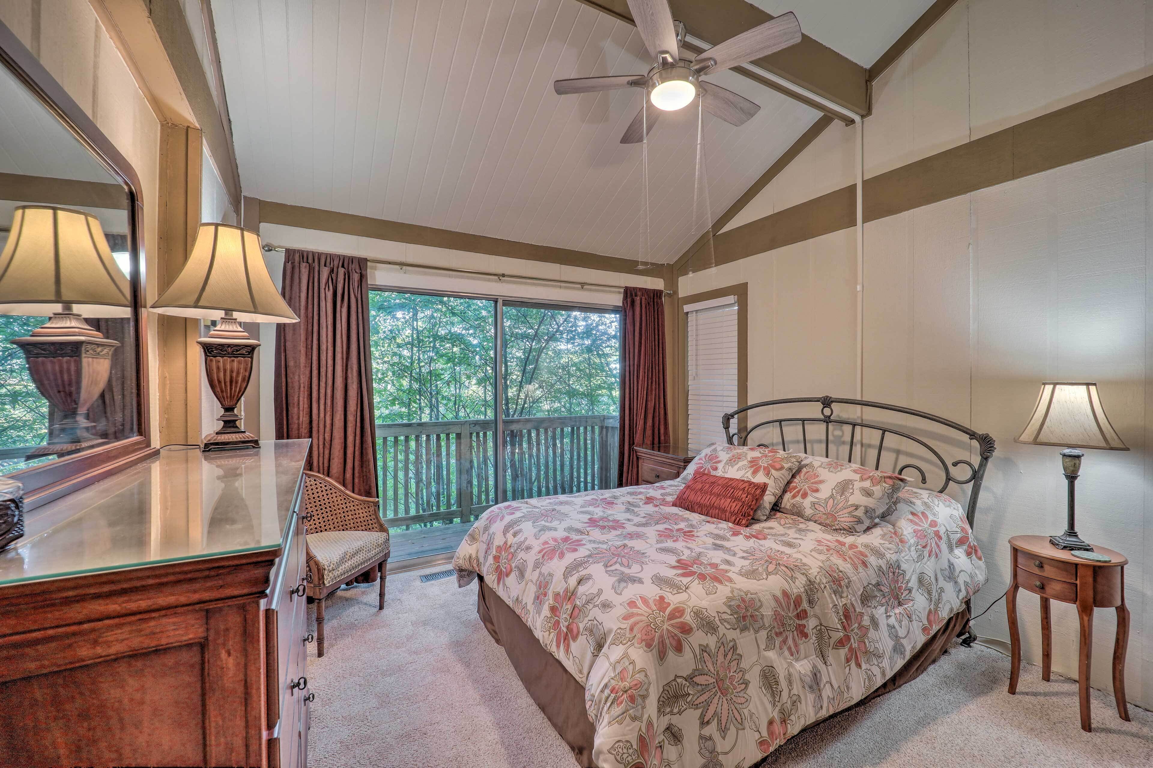 A bedroom with a bed, a dresser, a chair, a ceiling fan, and a window with curtains.