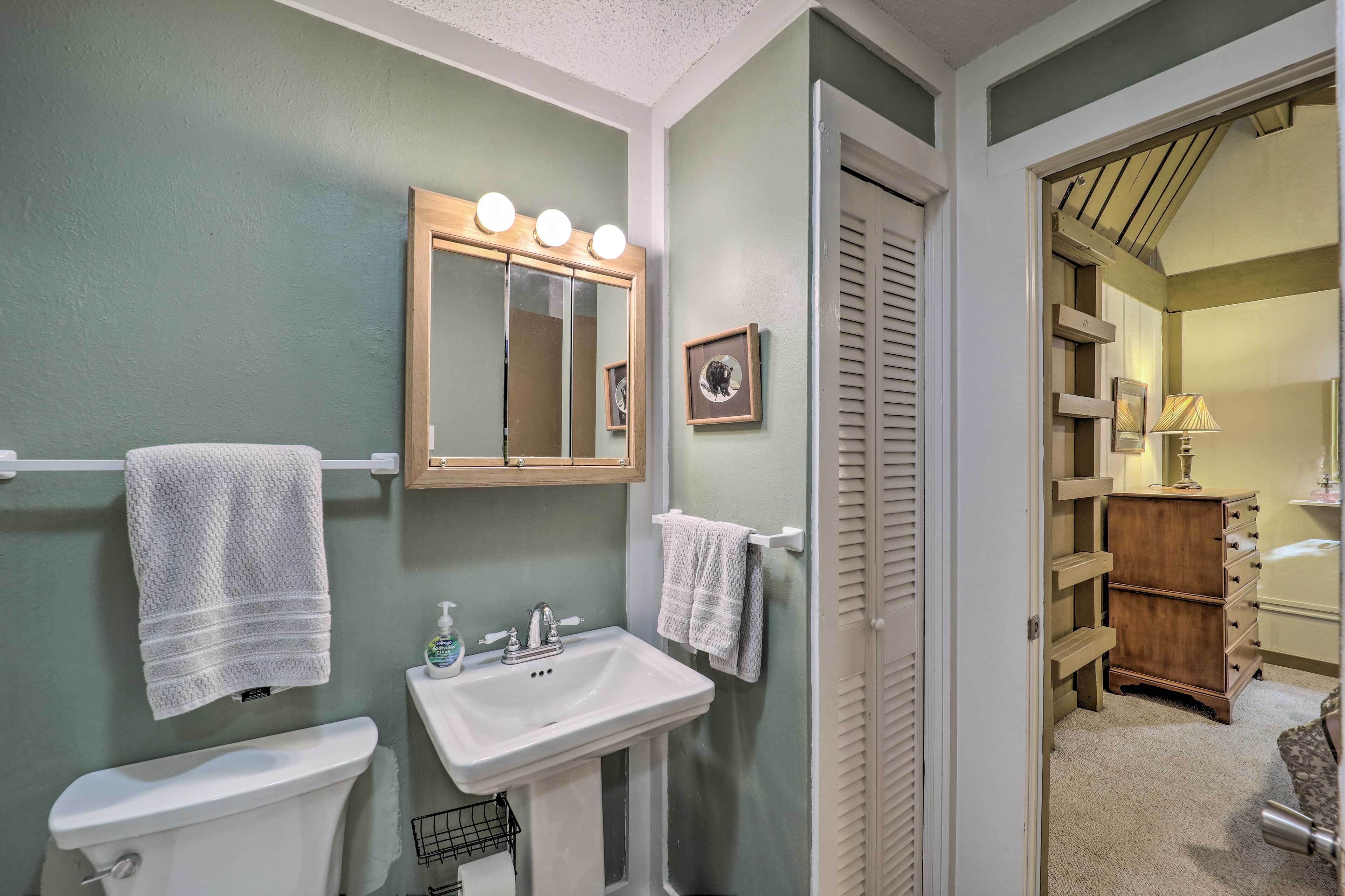 A bathroom with a sink, mirror, and towel rack. There is a wooden cabinet and a door leading to another room.