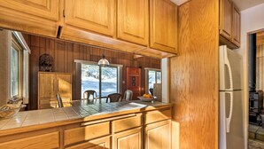 Une cuisine avec des meubles de rangement en bois, un plan de travail carrelé et un réfrigérateur.