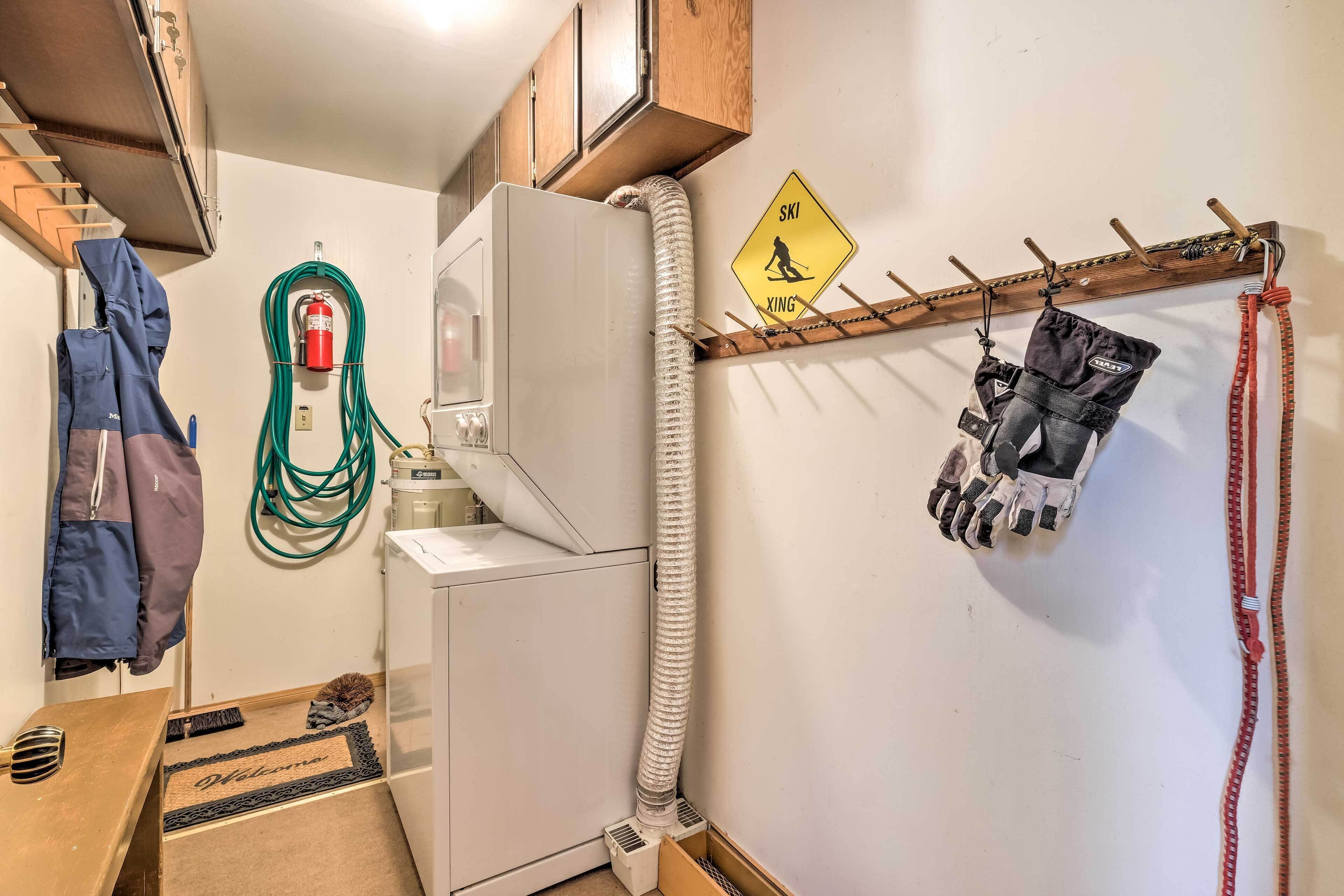 A corner of a room with a white heater, a fire extinguisher, a ski sign, and a coat rack with gloves and a red leash.