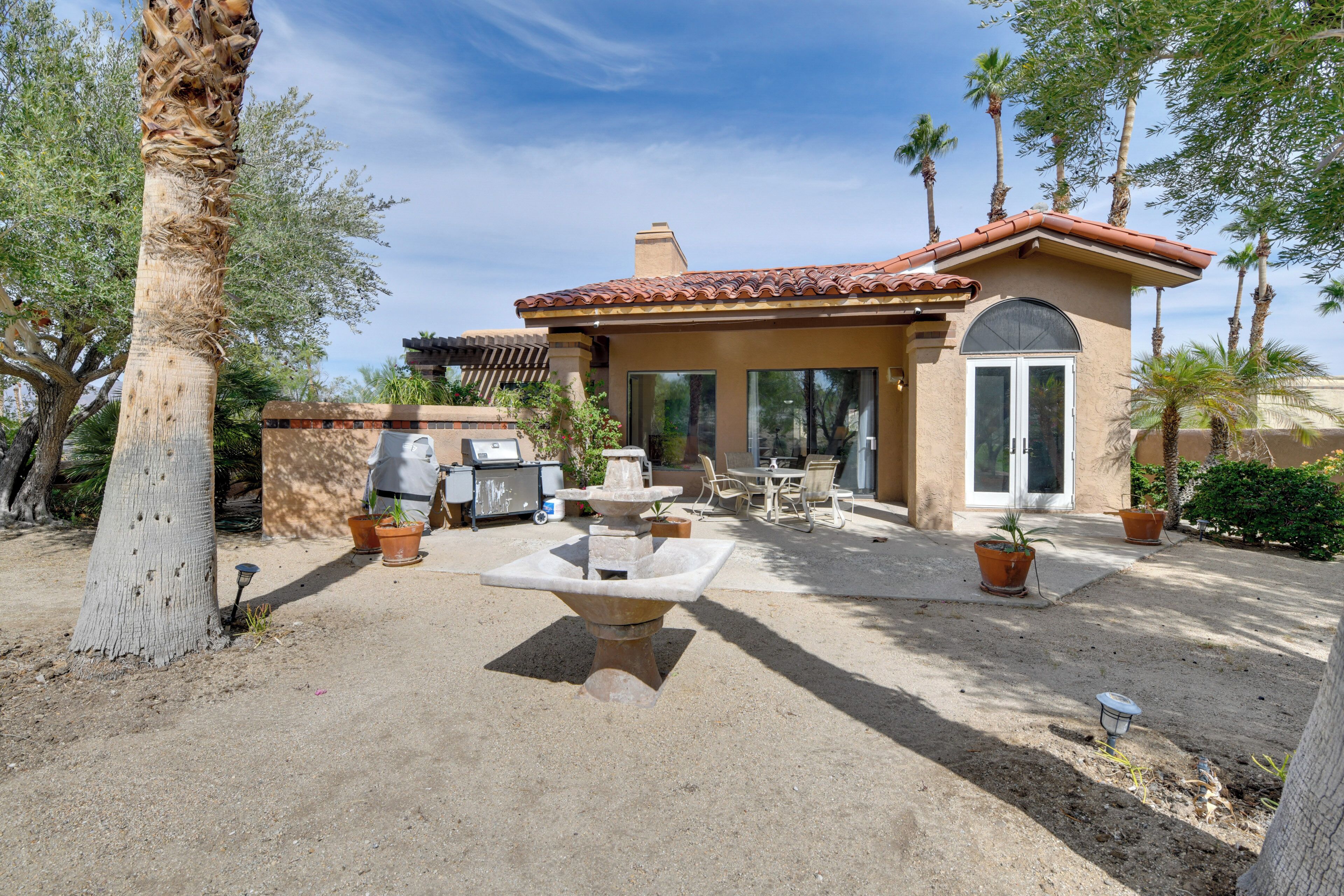 A patio with a stone fountain, outdoor furniture, and potted plants.