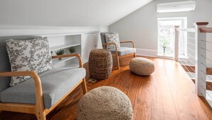 A cozy loft-style living room with a sloped ceiling, wooden flooring, and a built-in white shelving unit.
