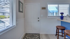 A hallway with a white door, a patterned rug, and a window with blinds.
