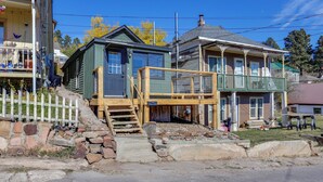 A two-story house with a porch, a wooden staircase, and a stone retaining wall. - Centrally-located Mountain Getaway in Lead! (Lead)