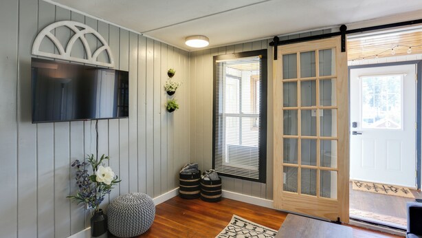 A room with a mounted TV, a wooden door with glass panels, a potted plant, and a small rug. - Centrally-located Mountain Getaway in Lead! (Lead)