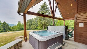A hot tub in a covered outdoor area with a stone bench and a view of the forest. - 3-acre Benezette Cabin: Hot Tub, Grill & Mtn View (Benezette)