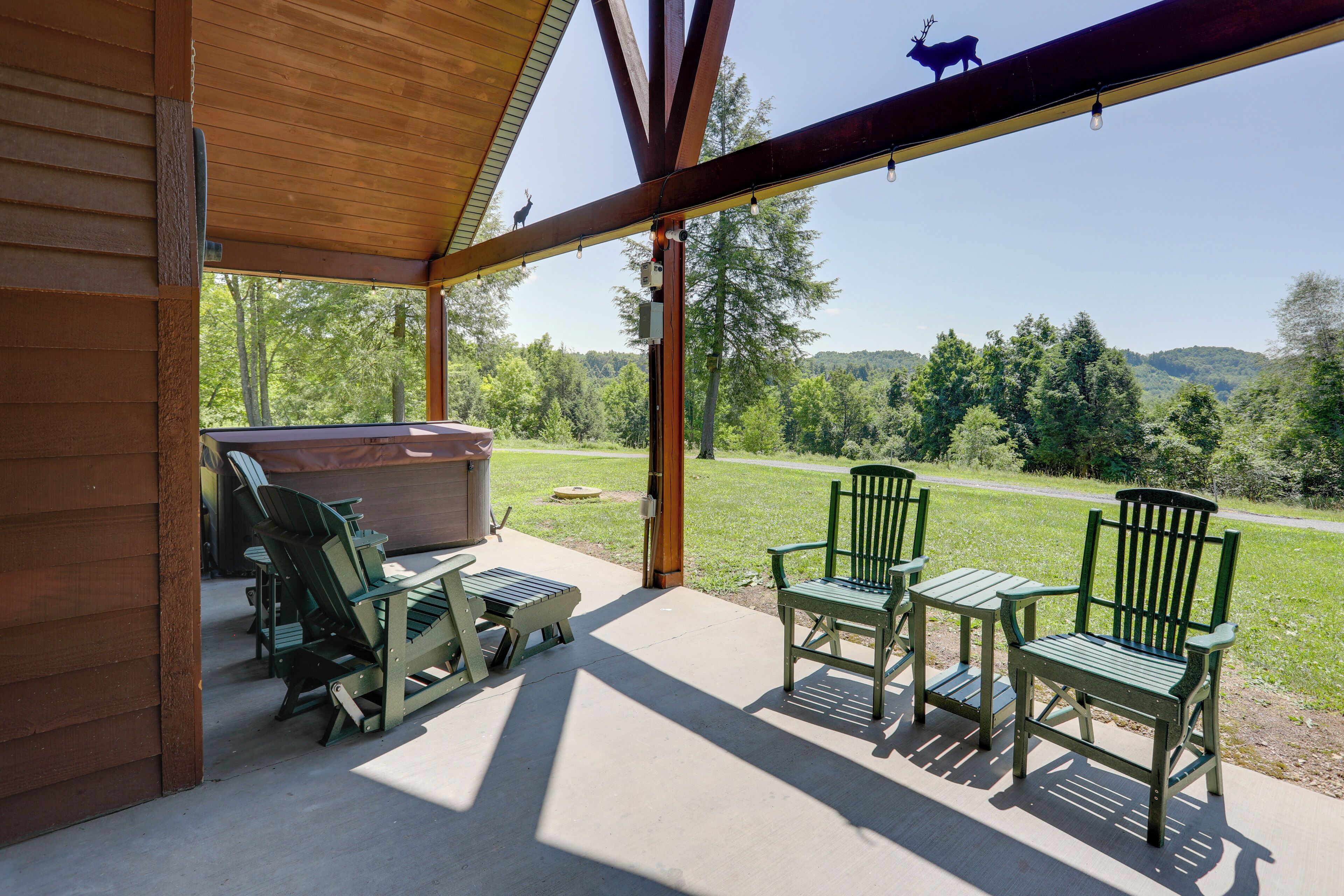 Un patio exterior con cubierta de madera, dos sillas Adirondack, una mesa y una parrilla.